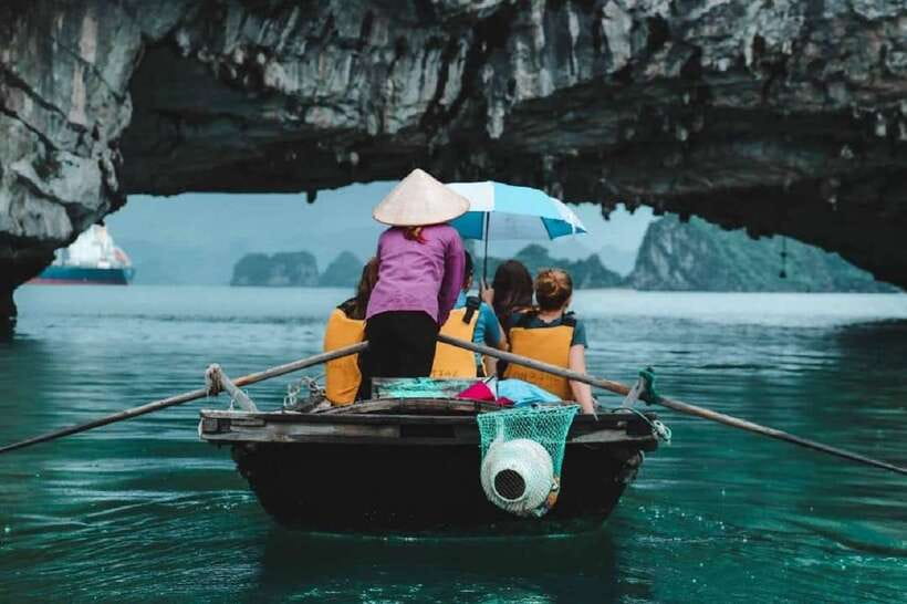 A rower crossing Ha Long Bay beneath the limestone karst